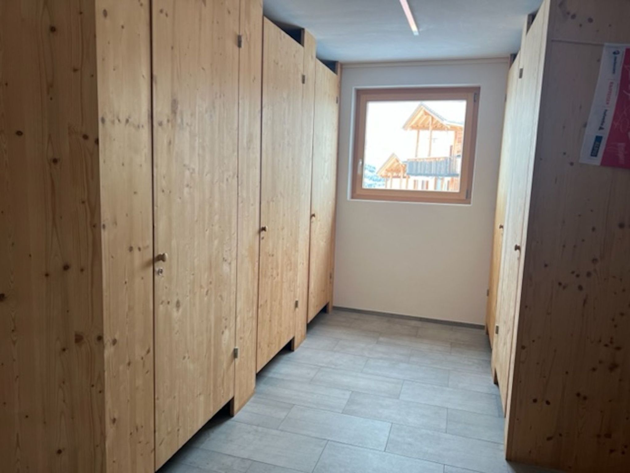 A narrow hallway with wooden walls and a window at the end.
