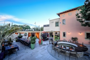 An outdoor patio area with tables and chairs, a round bar, and potted plants. - Aphrodite Hills Residences Superior Villas (Kouklia)