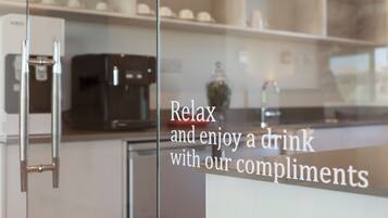 Eine moderne Küche mit Kaffeemaschine und Glastür, auf der steht, dass ein Getränk aufs Haus genossen werden kann.