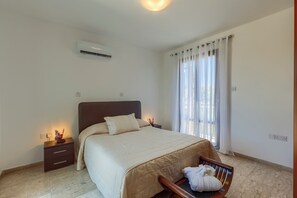 A bedroom with a bed, bedside table, nightstand, and a window with curtains. - Aphrodite Hills Residences Superior Villas (Kouklia)