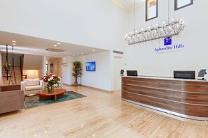 Een receptiebalie met een kroonluchter, een televisie en een wandbord voor Aphridite Hills Holiday Residences.