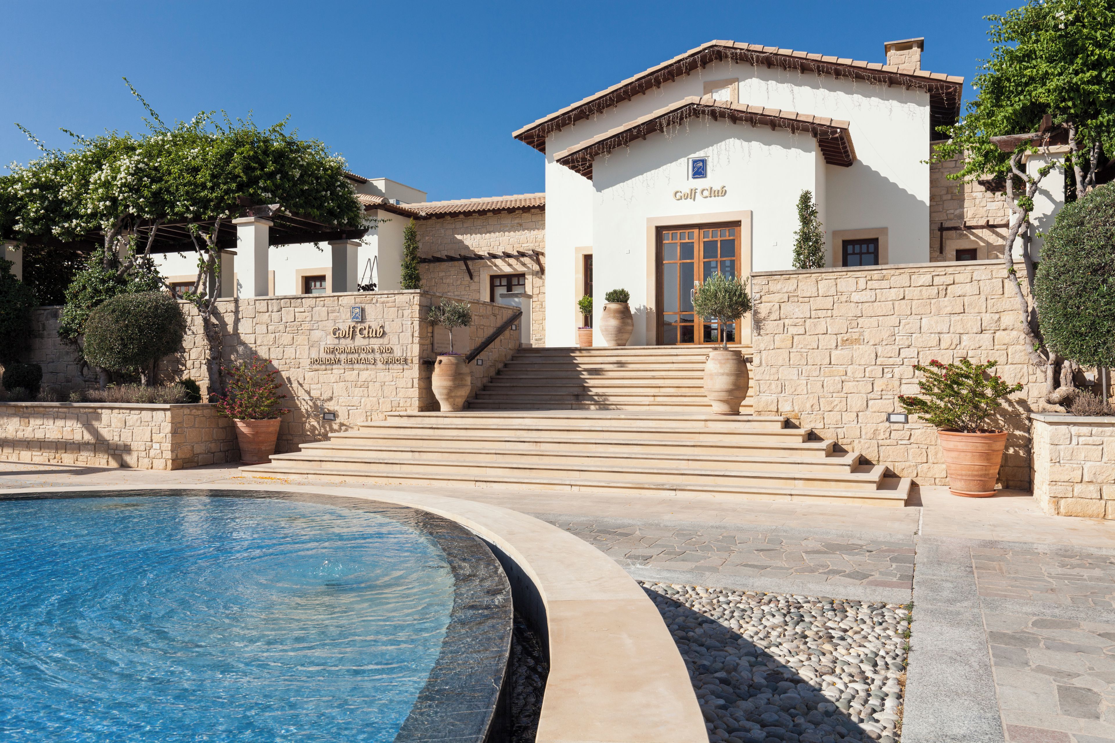 Un bâtiment sur lequel on peut lire l’inscription « Club de golf », avec une piscine au premier plan.