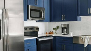 A kitchen with stainless steel appliances, blue cabinets, and a coffee maker. - Boulevard Stays Downtown Nashville (Nashville)