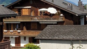 Eine Holzhütte mit Balkon, Schornstein und Bergblick.
