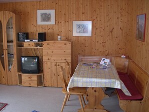 A wooden room with a bed, a television, a wooden cabinet, and a table with a placemat. - Schweizer, Obersaxen-Affeier, (Obersaxen), 34006B by Interhome (Obersaxen Affeier)