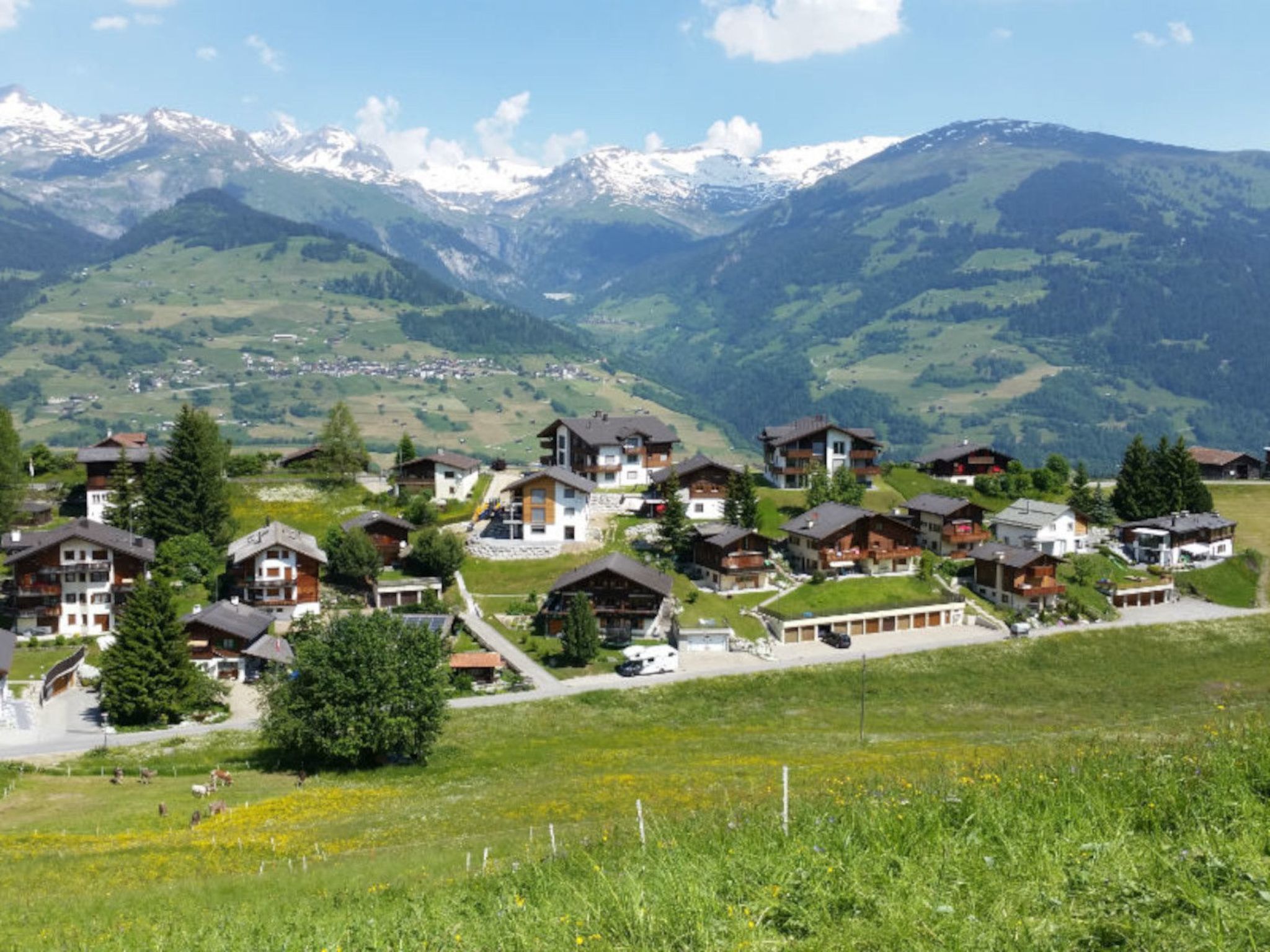 A village with houses surrounded by mountains and a clear sky.