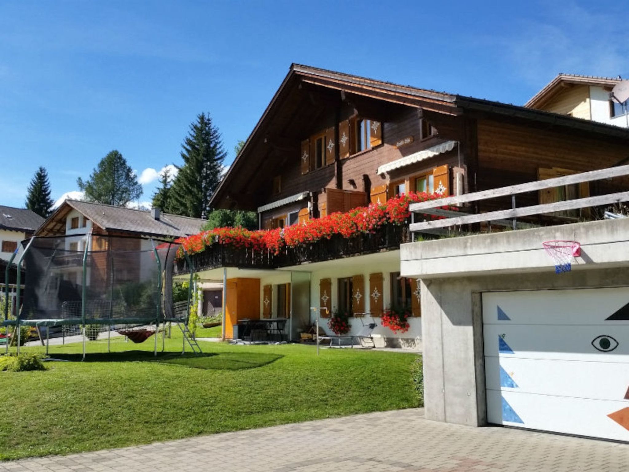 Ein Wohnhaus mit einer großen Garage, einem gepflegten Rasen und einem Trampolin im Garten.