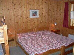 A wooden-paneled room with a bed, a nightstand, and a framed picture on the wall. - Schweizer, Obersaxen-Affeier, (Obersaxen), 34006B by Interhome (Obersaxen Affeier)