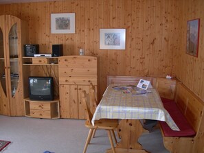 A wooden room with a television, a table with a placemat, and two framed pictures on the wall. - Schweizer, Obersaxen-Affeier, (Obersaxen), 34006B by Interhome (Obersaxen Affeier)
