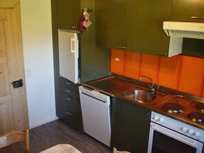 A compact kitchen with a dishwasher, stove, and sink. - Gyrgarta, Obersaxen-Meierhof, (Obersaxen), 34066B by Interhome (Obersaxen Affeier)