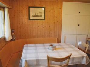 A wooden-paneled room with a table set for two, a framed picture on the wall, and a window with curtains. - Gyrgarta, Obersaxen-Meierhof, (Obersaxen), 34066B by Interhome (Obersaxen Affeier)