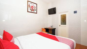 A hotel room with a bed, a desk, a TV, and a door.