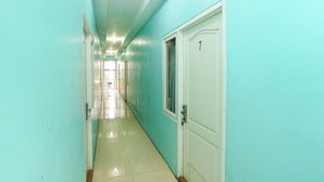 A hallway with teal walls and white doors, leading to a bright room at the end. - OYO 425 Mojokerto Guesthouse (Mojokerto)
