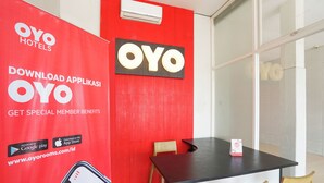 A hotel lobby with a red wall, a black table, and two wooden chairs. - OYO 425 Mojokerto Guesthouse (Mojokerto)