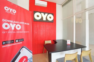 Un vestíbulo de hotel con una pared roja, una mesa negra y dos sillas de madera.