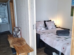 A bedroom with a bed, pillows, a bench, and a wooden bench with a fur throw.