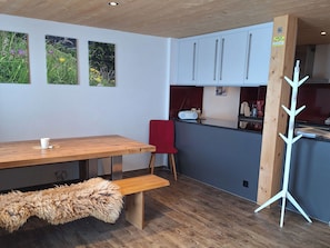 Eine moderne Küche mit Holzausstattung, einem roten Stuhl, einer Bank und einer weißen, baumartigen Dekoration.