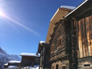 Un edificio de madera con techo inclinado, probablemente un chalé o una cabaña de montaña, con cielo despejado y suelo cubierto de nieve.