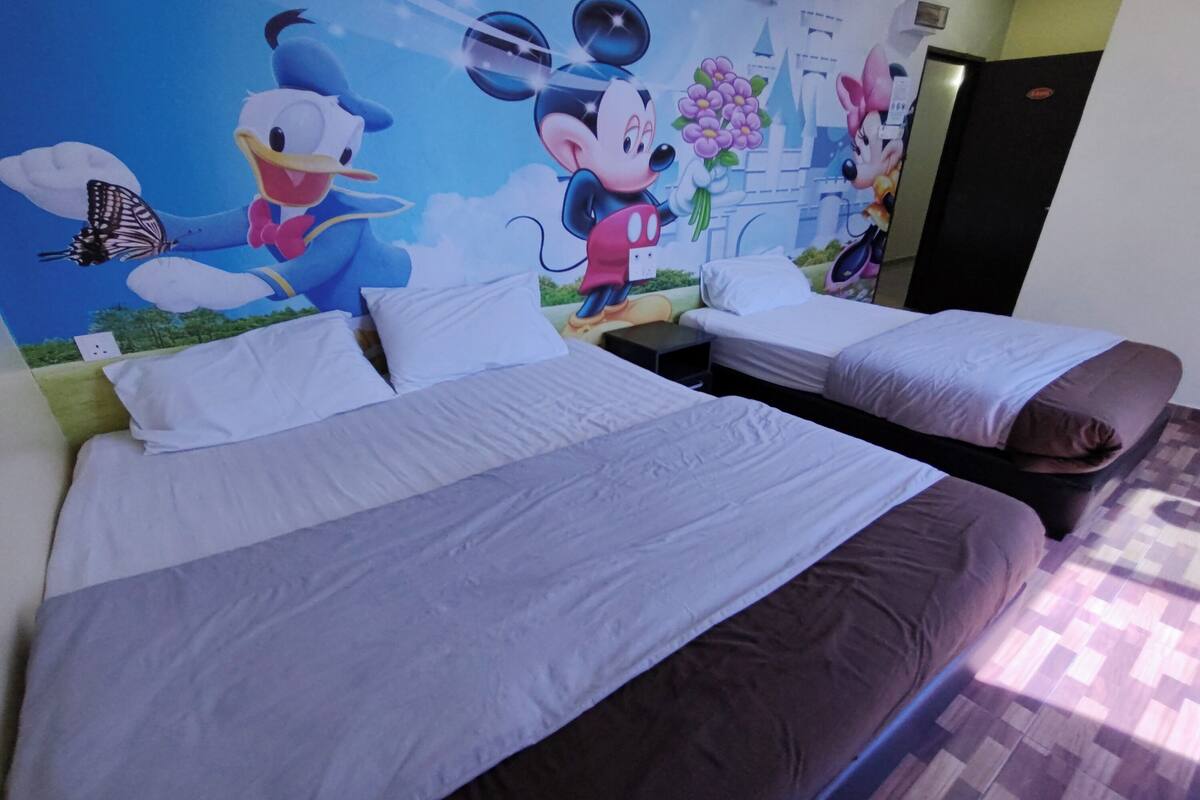 A hotel room with two beds, a Mickey Mouse mural, and a door with a mirror.