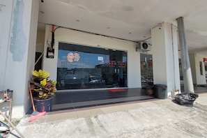 A hotel entrance with a glass door, a potted plant, a broom, and a trash bin. - Nova Hotel Ipoh by Zuzu (Ipoh)
