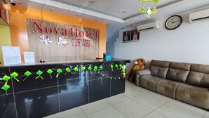 A reception desk with a sign reading 'Nova Hotel' and a brown couch with a teddy bear. - Nova Hotel Ipoh by Zuzu (Ipoh)