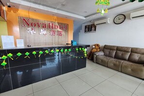 A reception desk with a sign reading 'Nova Hotel' and a brown couch with a teddy bear. - Nova Hotel Ipoh by Zuzu (Ipoh)