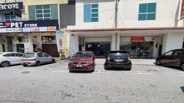 A parking lot with several cars, a pet store, and a building with a red awning. - Nova Hotel Ipoh by Zuzu (Ipoh)