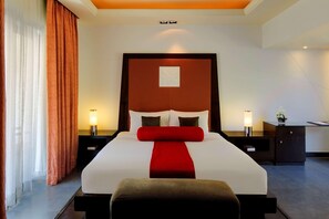 A hotel room with a large bed, two bedside tables with lamps, a desk, and a chair.