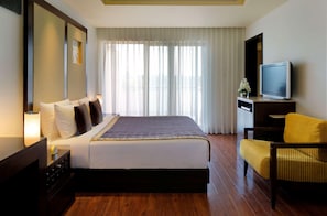 A hotel room with a bed, a television, a chair, and a desk. - Radisson Blu Resort & Spa Alibaug (Alibag)
