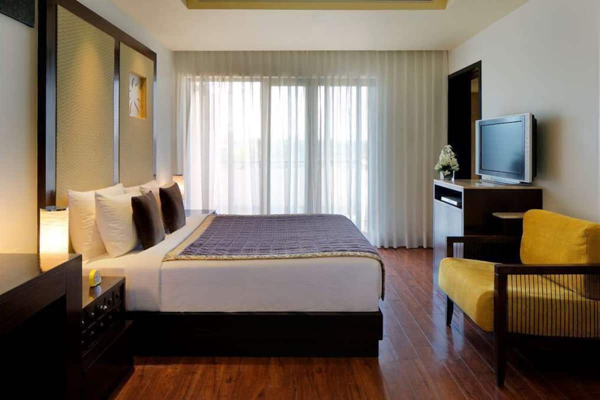 A hotel room with a bed, a television, a chair, and a desk.