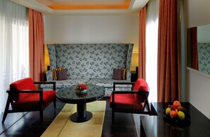 A modern living room with a sofa, two armchairs, a coffee table, and a fruit bowl. - Radisson Blu Resort & Spa Alibaug (Alibag)