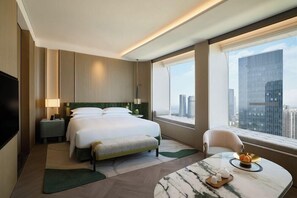 A hotel room with a large bed, a desk with a marble top, a chair, a window with a city view, and a television. - Fairmont Xiamen (Xiamen)