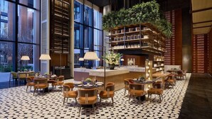 A modern hotel lobby with a geometric patterned floor, a central seating area with round tables and chairs, and a vertical garden feature. - Fairmont Xiamen (Xiamen)