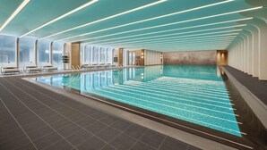 A large indoor swimming pool with a modern design, including a patterned floor and ceiling lights. - Fairmont Xiamen (Xiamen)