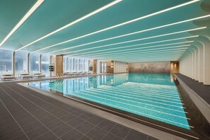 A large indoor swimming pool with a modern design, including a patterned floor and ceiling lights. - Fairmont Xiamen (Xiamen)