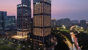 A high-rise building with a modern design, surrounded by other high-rise buildings and a busy road. - Fairmont Xiamen (Xiamen)