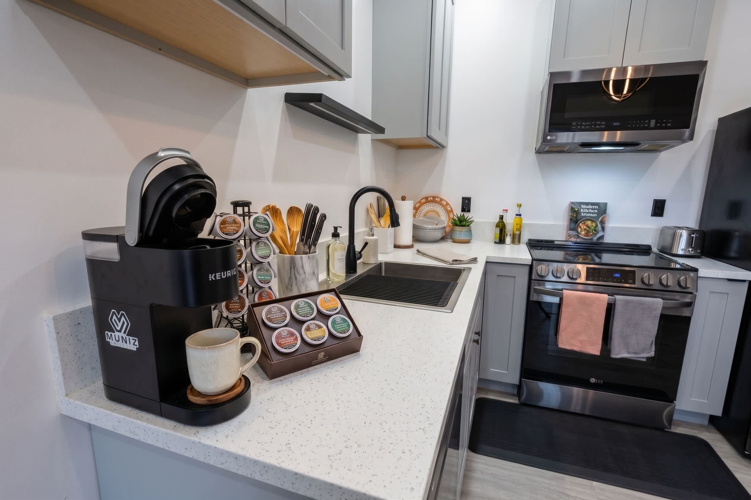 Una cucina moderna con una macchina per il caffè, una tazza, un set di coltelli, un lavello e un fornello.
