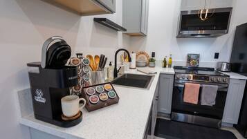 Una cucina moderna con una macchina per il caffè, una tazza, un set di coltelli, un lavello e un fornello.