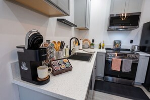 Una cucina moderna con una macchina per il caffè, una tazza, un set di coltelli, un lavello e un fornello.
