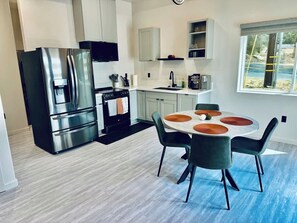 A modern kitchen with a stainless steel refrigerator, a built-in oven, and a dining area with a round table and chairs. - Escape to Muniz Village Unit A (Three Rivers)