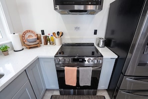 A modern kitchen with a built-in stove, oven, and a stainless steel refrigerator. - Sequoia Basecamp: Relaxing Retreat w/ Courtyard (Three Rivers)