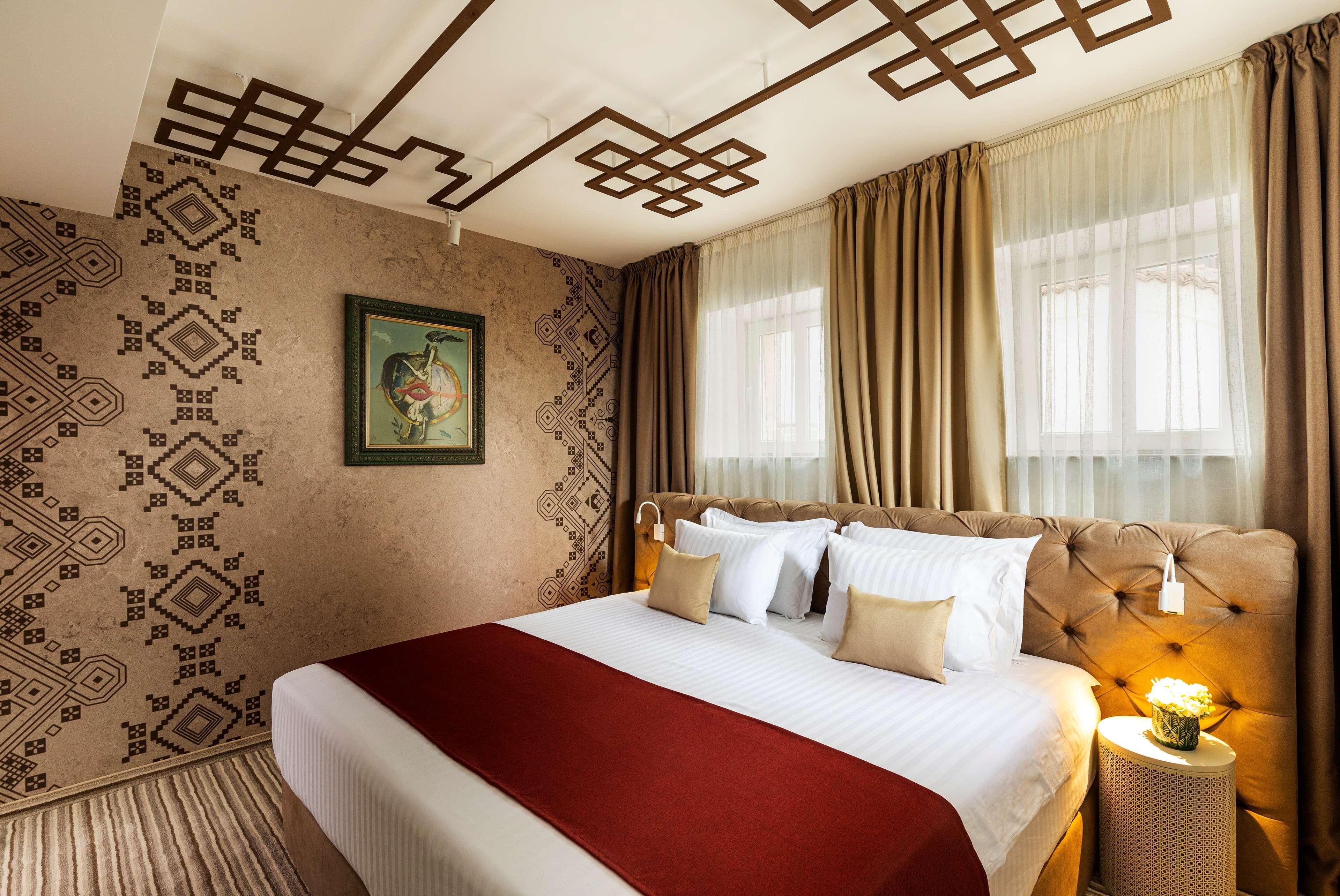 Una habitación de hotel con una cama grande, una pared decorativa y una ventana con cortinas.