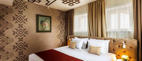 Una habitación de hotel con una cama grande, una pared decorativa y una ventana con cortinas.