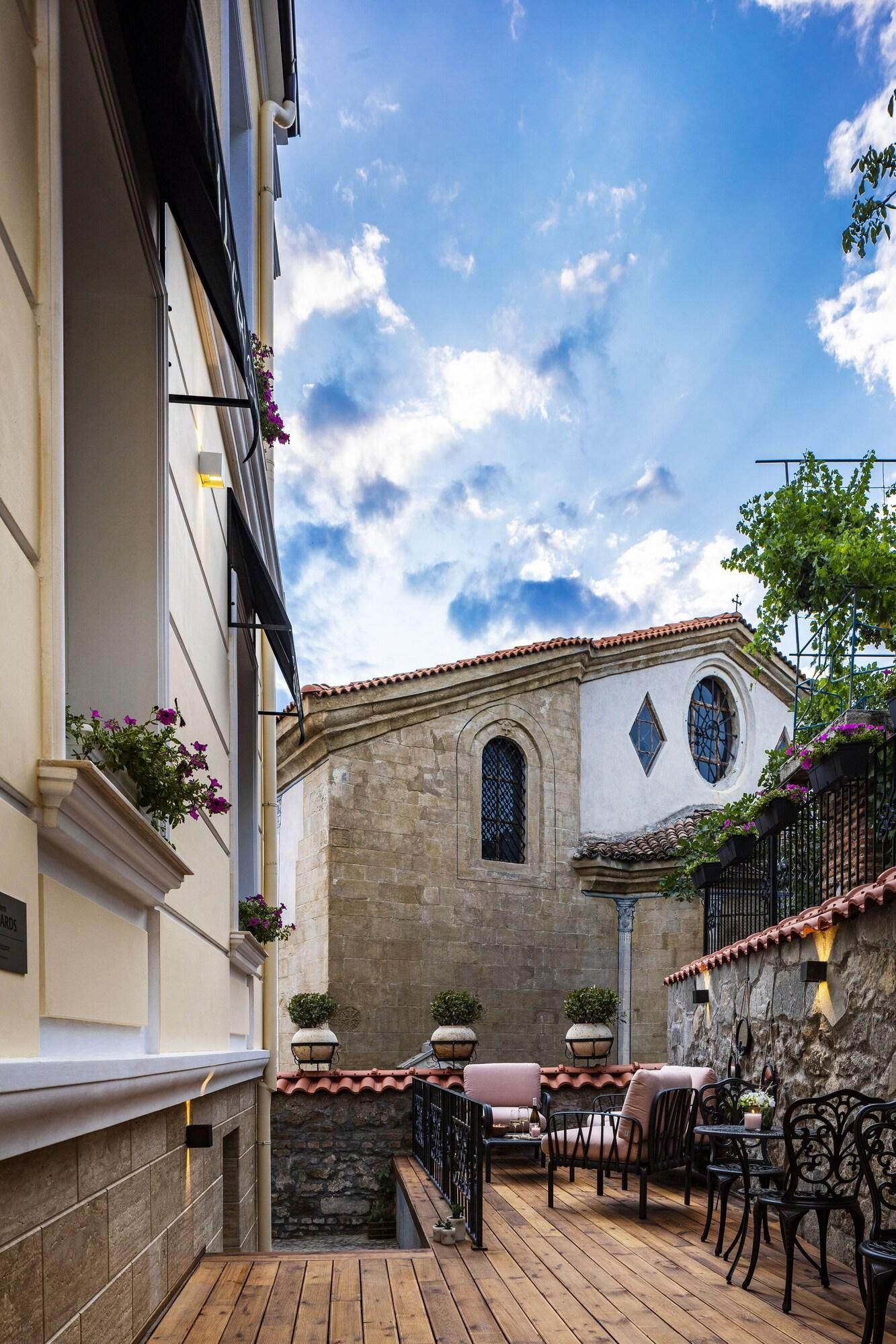 A courtyard with a stone wall, a wooden deck, and outdoor seating.