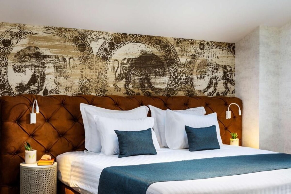 Un dormitorio con cabecera capitonada, ropa de cama blanca y un tapiz decorativo en la pared.