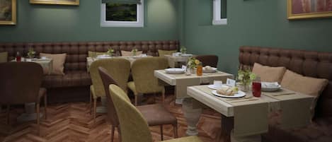 A restaurant with booths and tables, wooden herringbone flooring, and green walls.