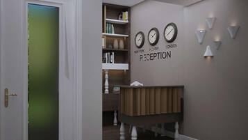 A reception area with a wooden reception desk, a bookshelf with books, and wall clocks displaying times from New York, Plymouth, and London.