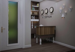 A reception area with a wooden reception desk, a bookshelf with books, and wall clocks displaying times from New York, Plymouth, and London. - Gallery 37, BW Premier Collection (Plovdiv)