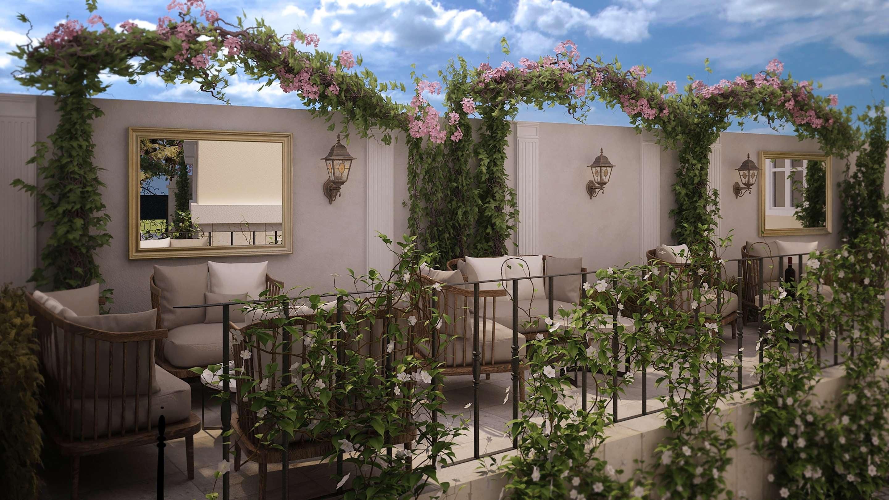 An outdoor seating area with cushioned chairs, a table, and a pergola covered with flowering vines.