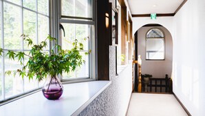 Un pasillo con ventana, una planta en maceta y un arco que conduce a otra habitación.